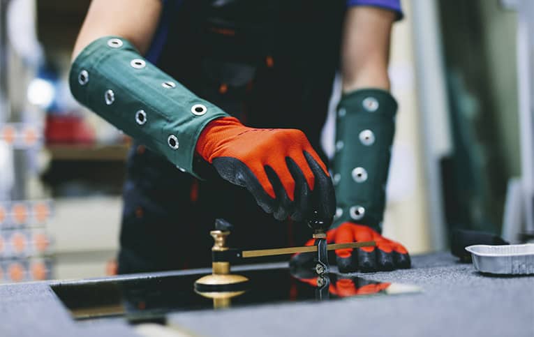 foto de vidraceiro com luvas posicionando equipamento para demonstrar como usar cortador de vidro