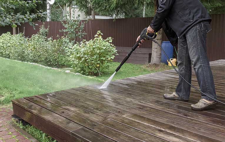 Pessoa usando lavadora de alta pressão em piso