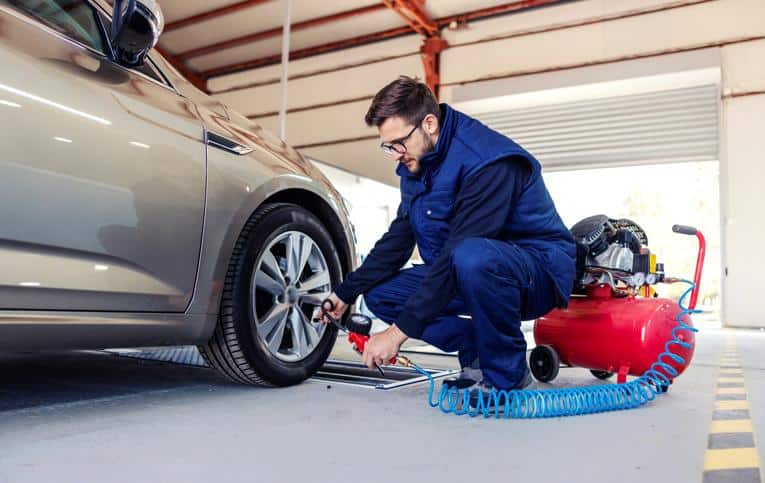 Homem usando compressor de ar em pneu de carro