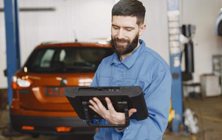 homem segurando equipamento em frente ao carro representando qual o melhor scanner automotivo