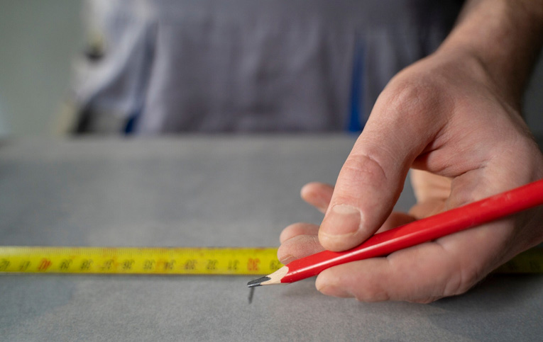 profissional usando trena e lápis para marcar superfície demonstrando como calcular metro quadrado de piso