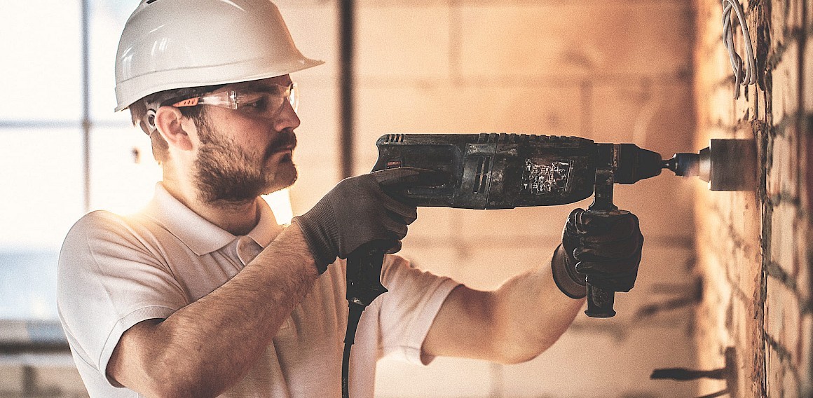 Profissional utilizando martelete perfurador em parede de alvenaria, exemplo prático de como escolher martelete conforme o tipo de trabalho