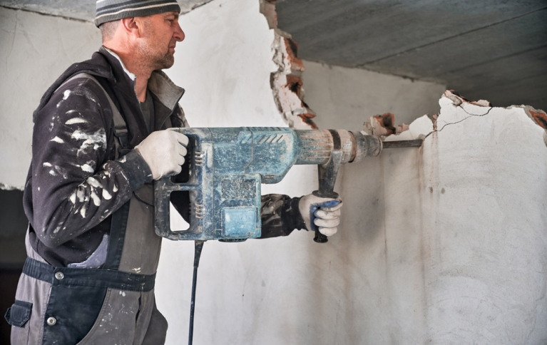 homem utilizando um tipo de martelete elétrico na construção