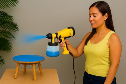 Mulher utilizando uma pistola de pintura elétrica com fio para pintar um banco de madeira com tinta azul.